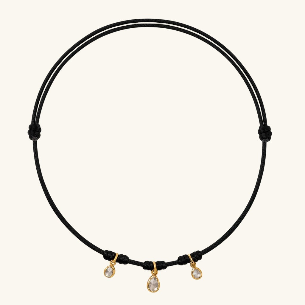 Brown cord necklace with three small diamonds on a white background