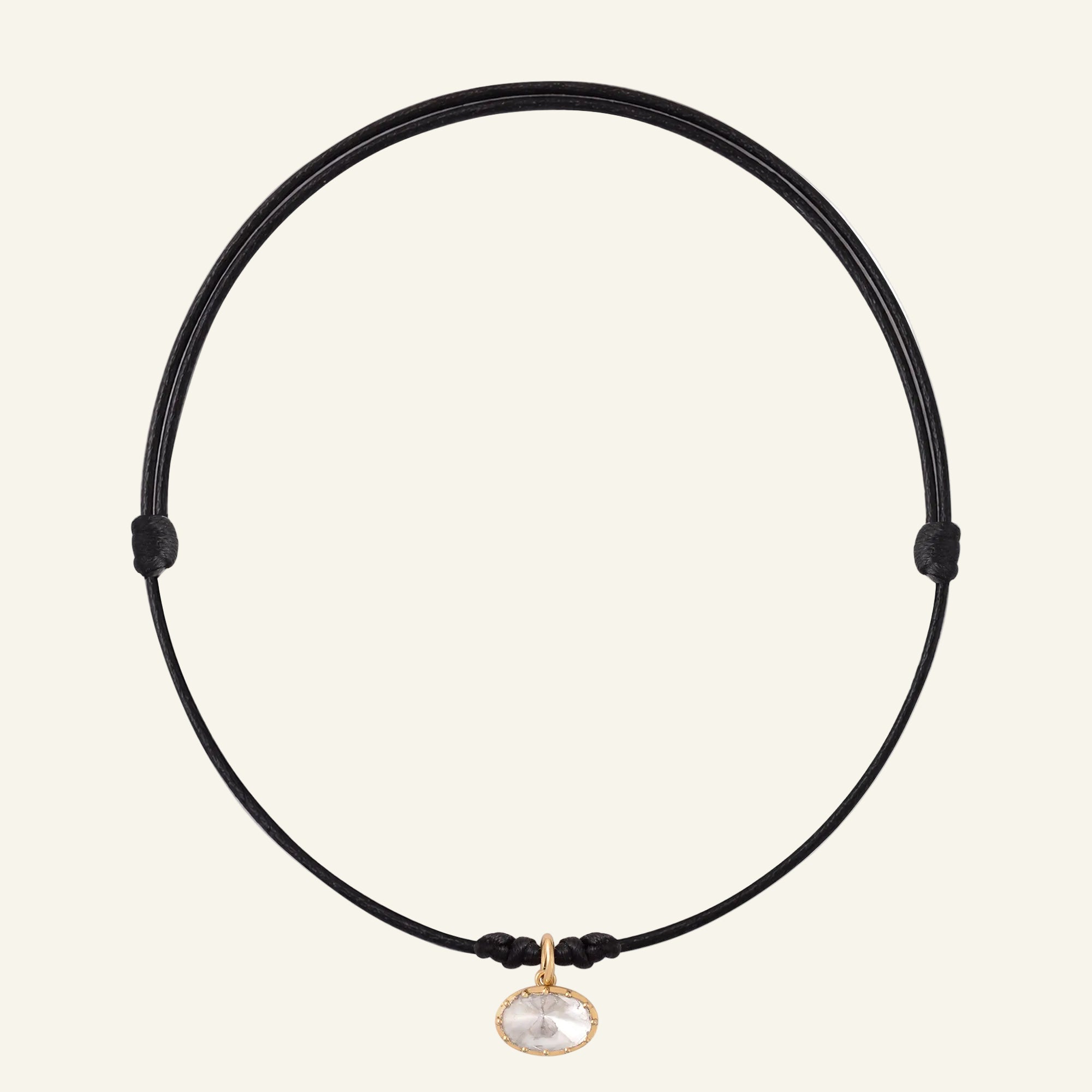 Black cord necklace with a gold clasp and pendant on a white background