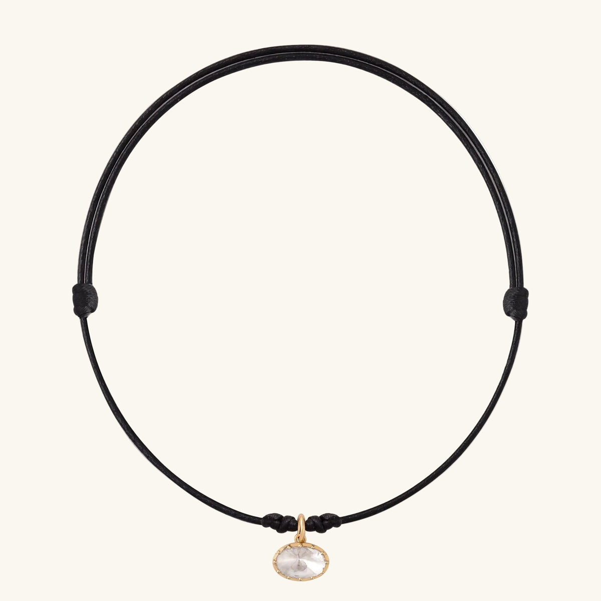 Black cord necklace with a gold clasp and pendant on a white background