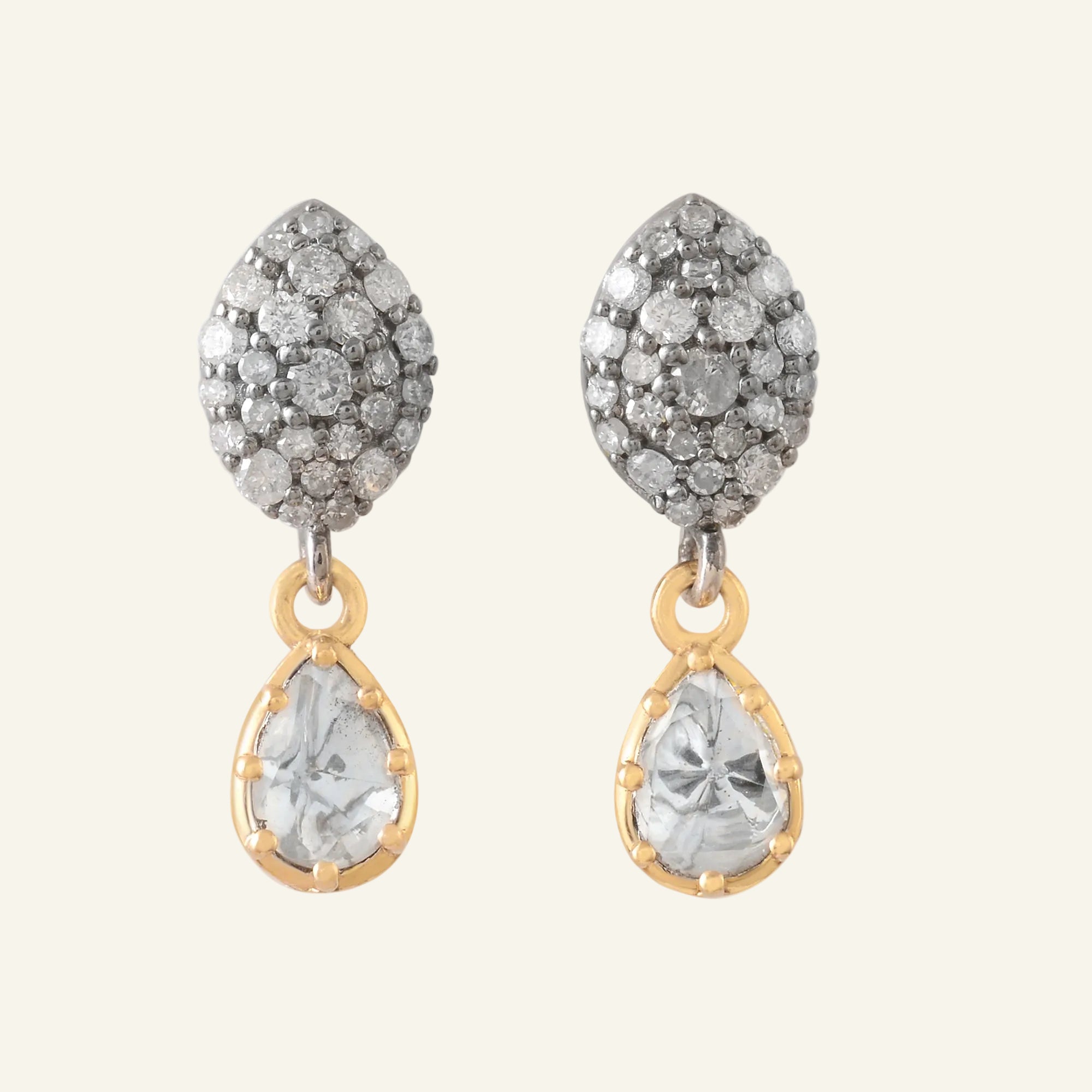 Pair of earrings with diamond-studded tops and diamond teardrop stones on a white background