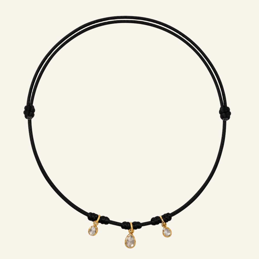 Brown cord necklace with three small diamonds on a white background